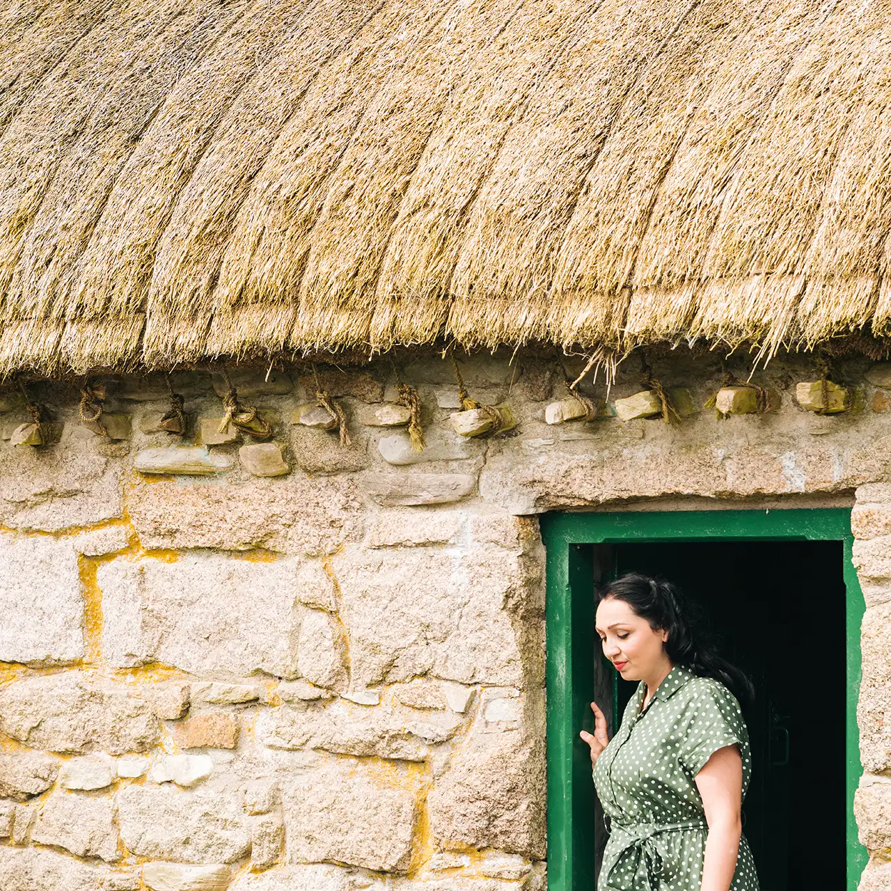 actor Katarina Kokenyova standing at the door of a cottage